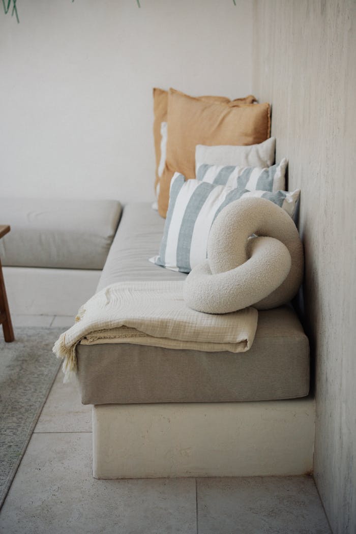 A cozy and minimalist living room with pillows and a decorative throw.