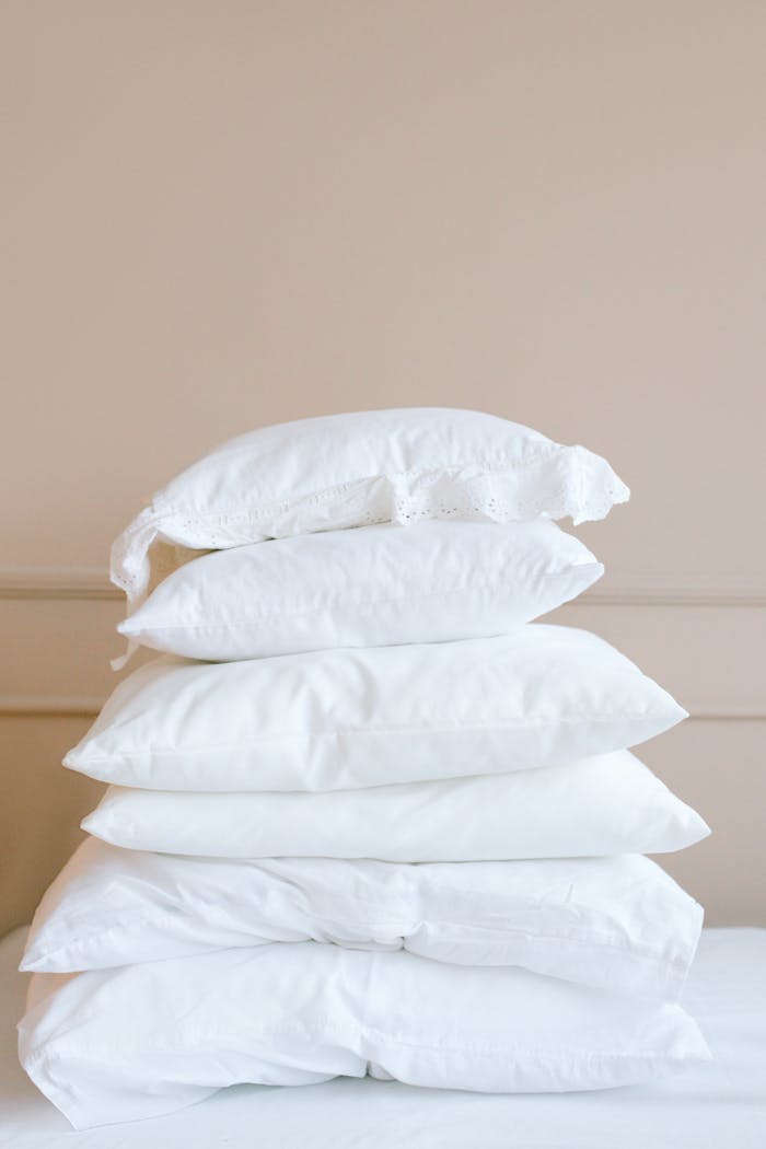 A stack of white pillows on a neutral background, showcasing elegance and simplicity.